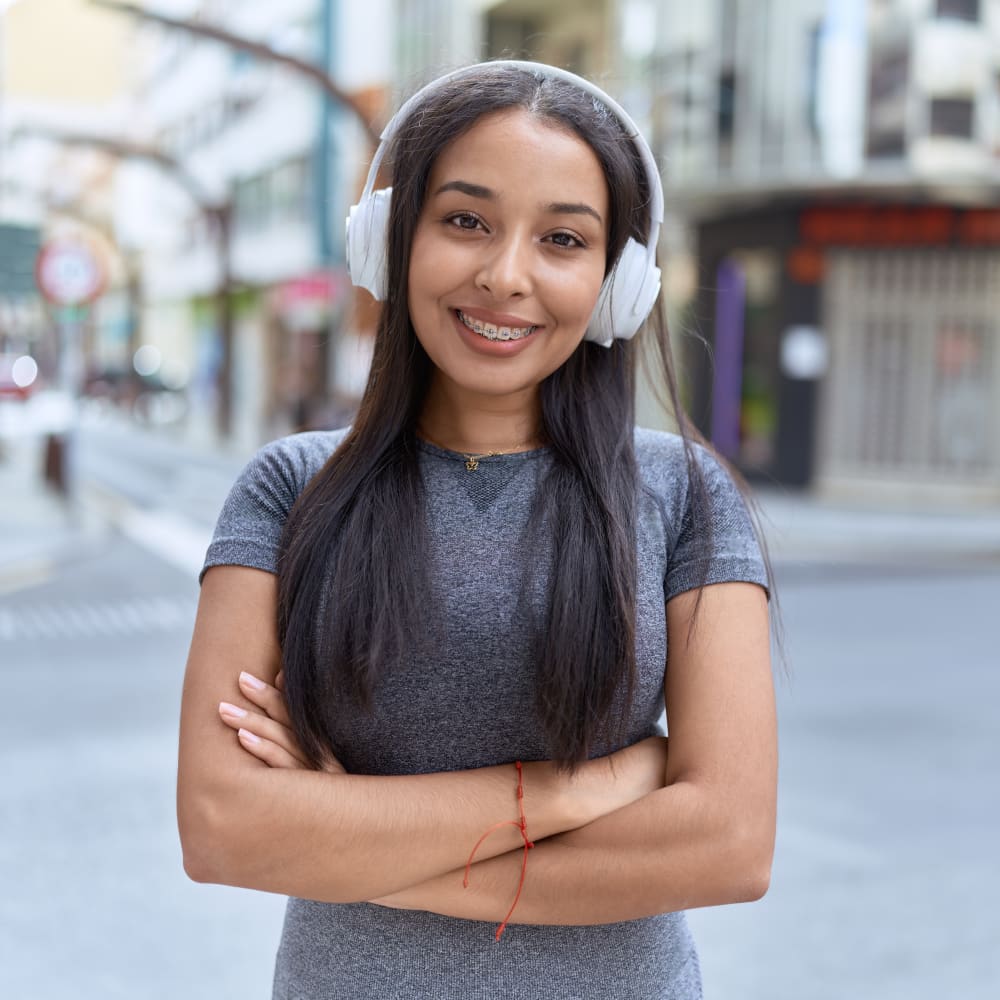 A woman stands outside smiling wide, showing off her braces.