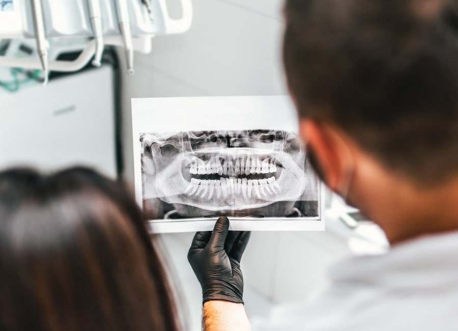 A dental professional holds up a panormaic X-ray.