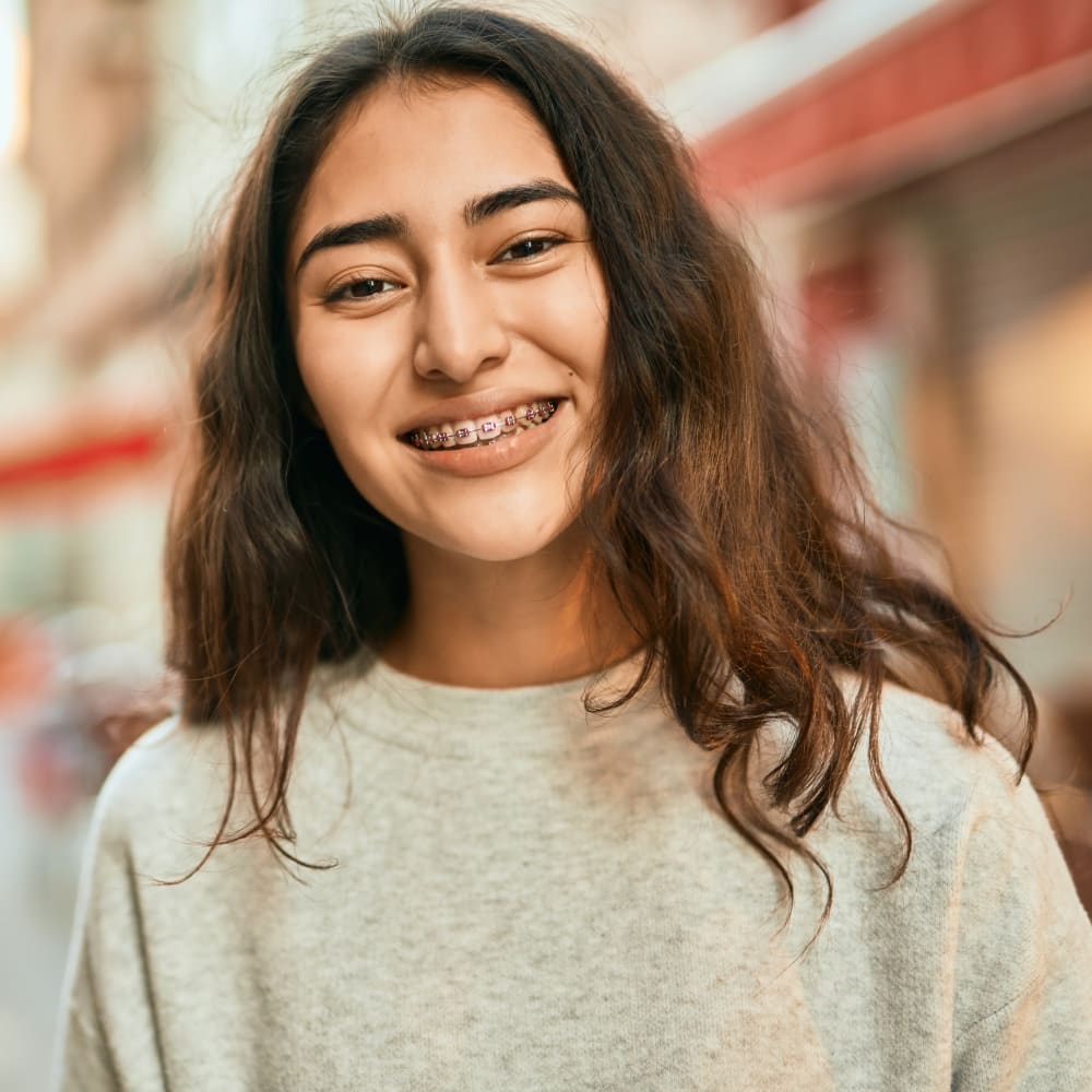A teen girl smiles while wearing braces,
